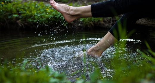 A girl tapping water with legs in a forest during the day